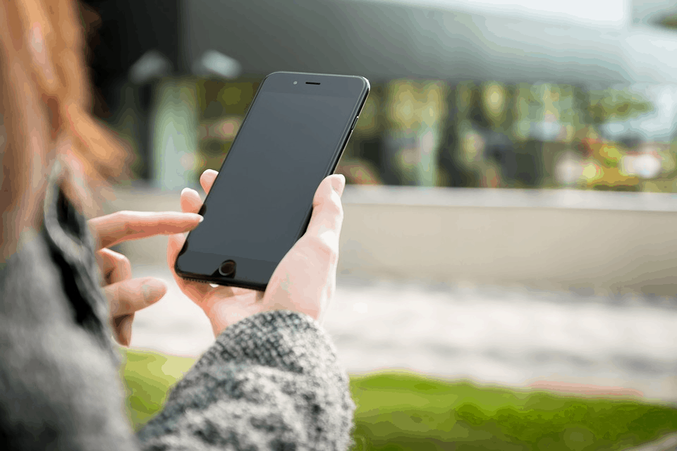 A woman holding a smartphone with a blank screen