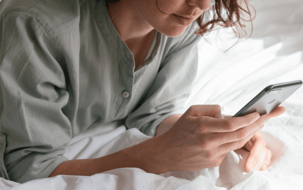 A woman holding her phone in bed 