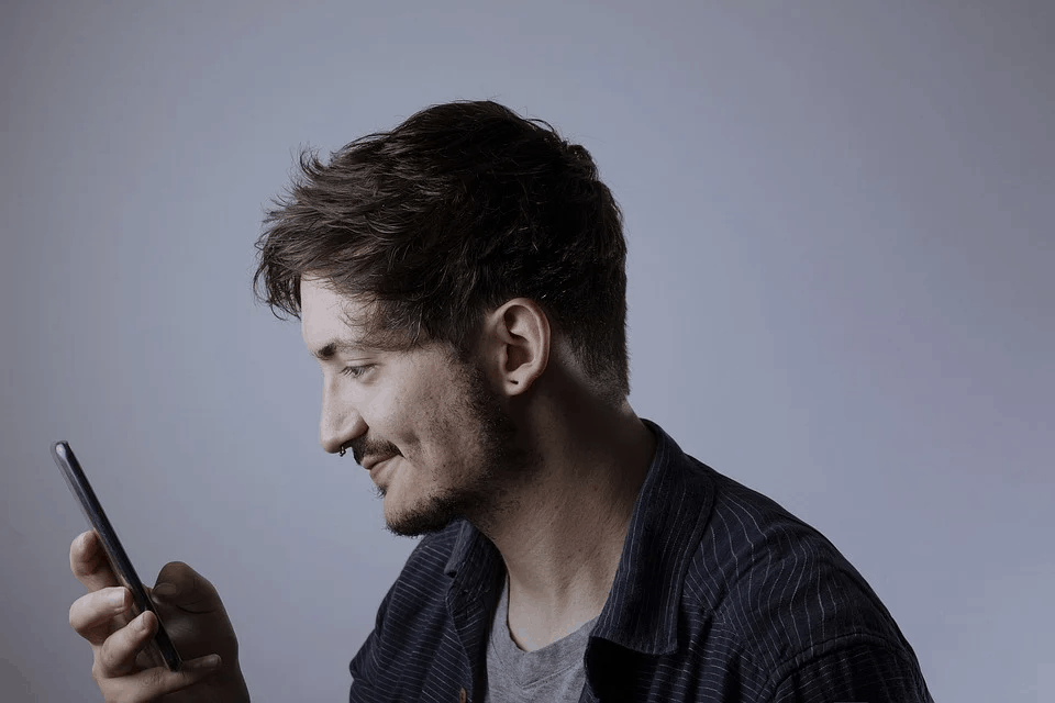 A young man holding his phone smiling because he has CallApp