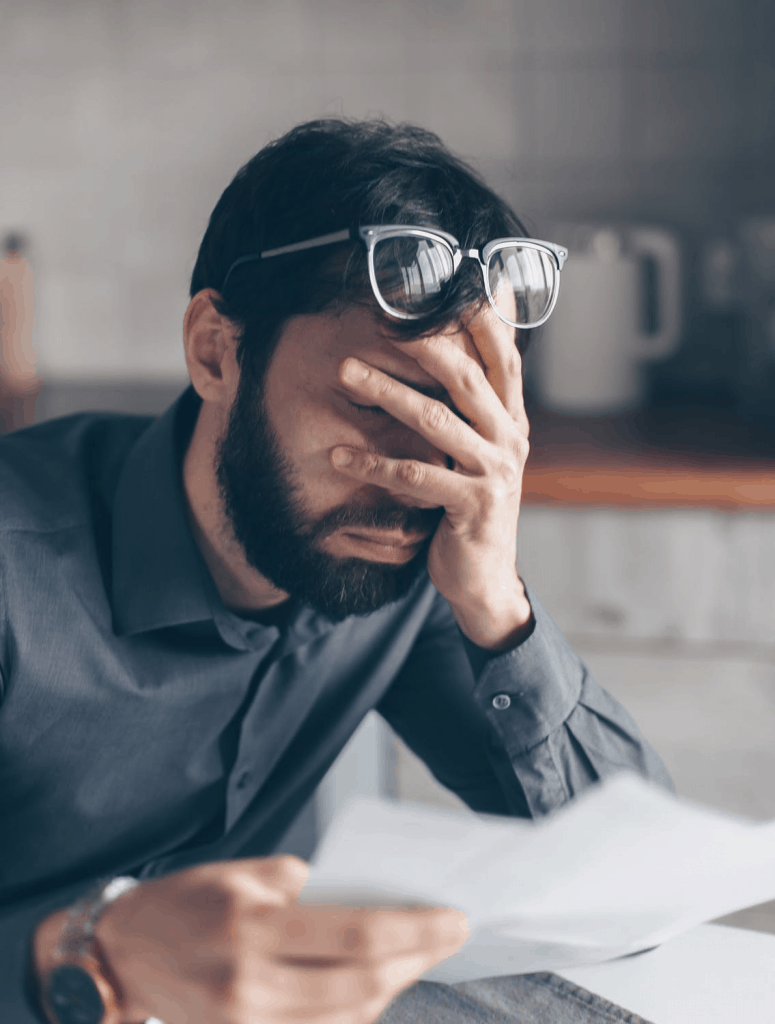 A man holding his face in dismay as he discovers he's been scammed 