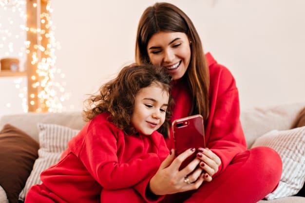 A mother and daughter wearing matching outfits as they look at a smartphone
